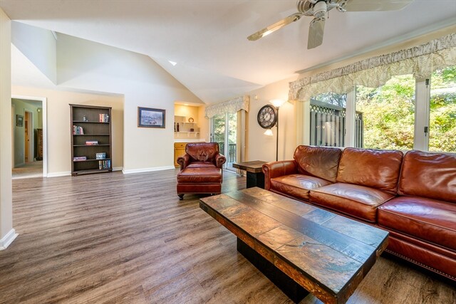 living room featuring built in features, a ceiling fan, vaulted ceiling, wood finished floors, and baseboards