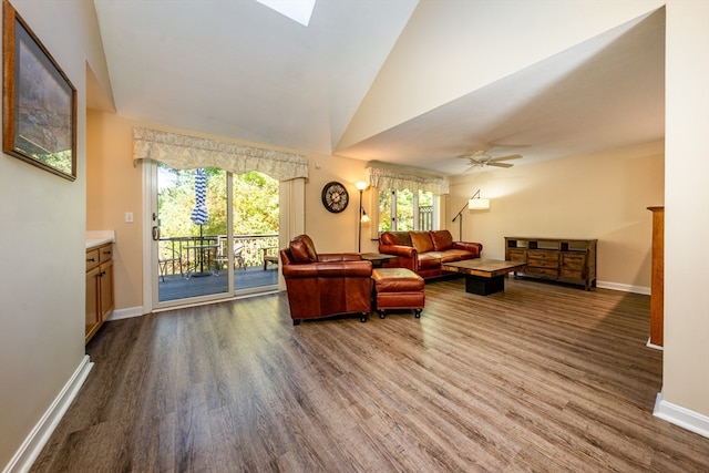 living area featuring dark wood-type flooring, a skylight, and baseboards