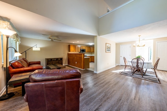 living area featuring baseboards, dark wood-style flooring, and ceiling fan with notable chandelier