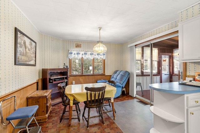 dining space with wallpapered walls, a chandelier, and a wainscoted wall