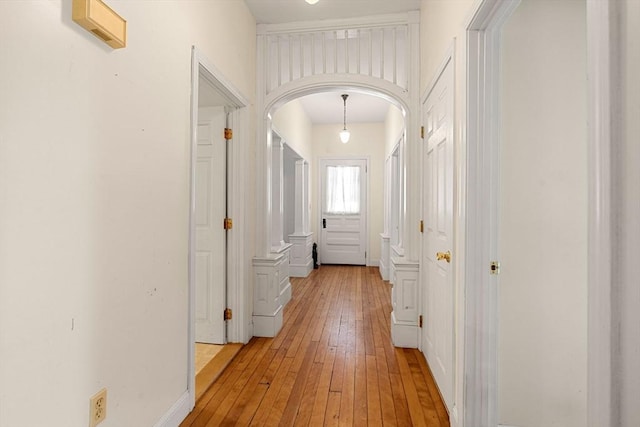 hall with light wood finished floors and arched walkways