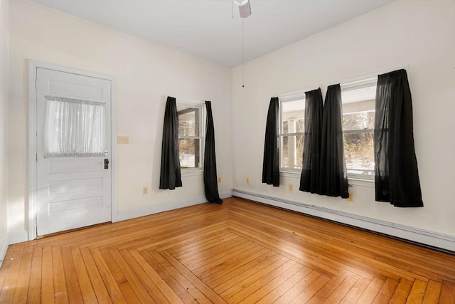 empty room featuring a baseboard heating unit, ceiling fan, and baseboards