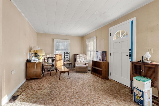 sitting room featuring carpet floors, visible vents, crown molding, and baseboards