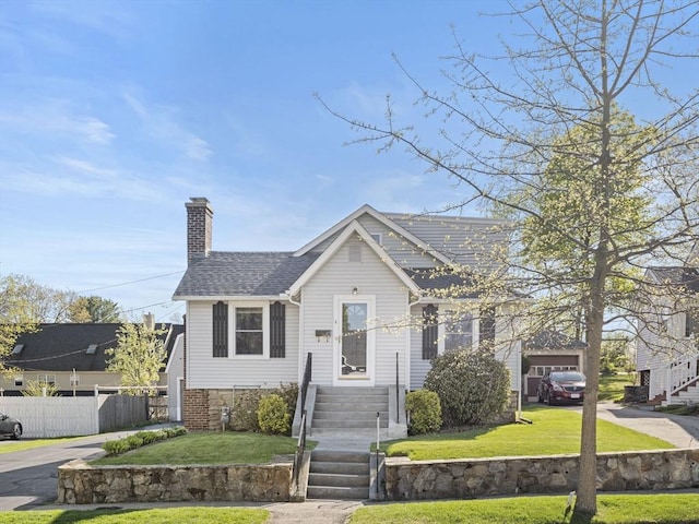 bungalow-style home with a shingled roof, a front lawn, fence, and a chimney