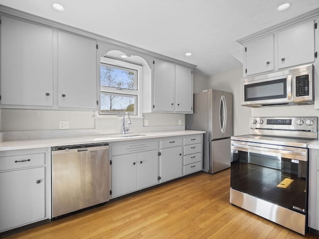 kitchen with light countertops, stainless steel appliances, a sink, and light wood-type flooring