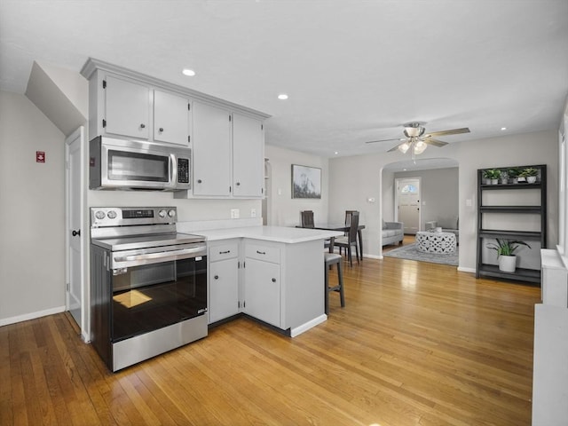 kitchen with a ceiling fan, light countertops, baseboards, a peninsula, and stainless steel appliances