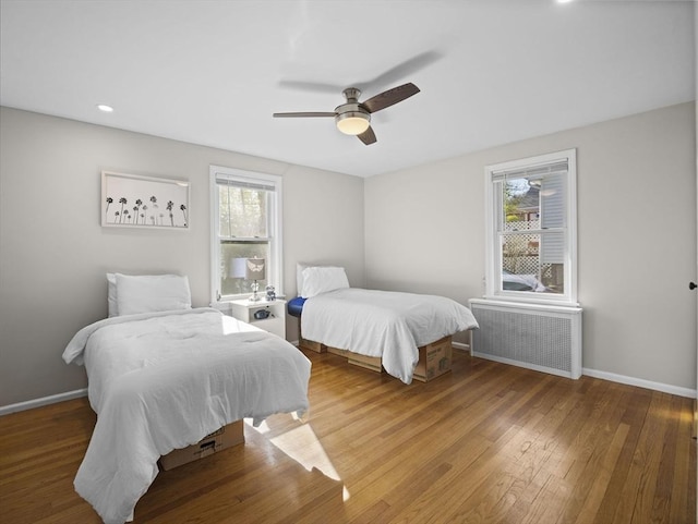 bedroom with multiple windows, wood finished floors, and radiator