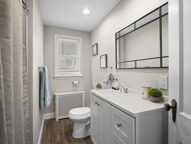 bathroom featuring vanity, toilet, radiator, baseboards, and wood finished floors