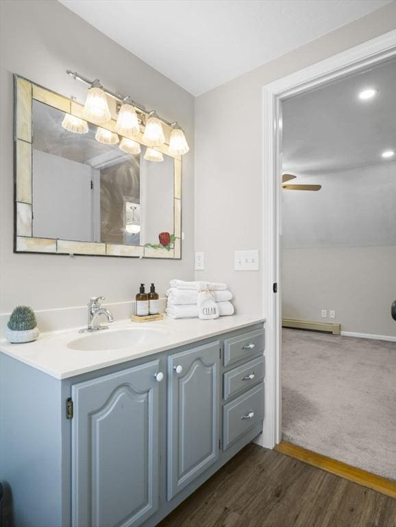 bathroom with ceiling fan, a baseboard radiator, wood finished floors, and vanity
