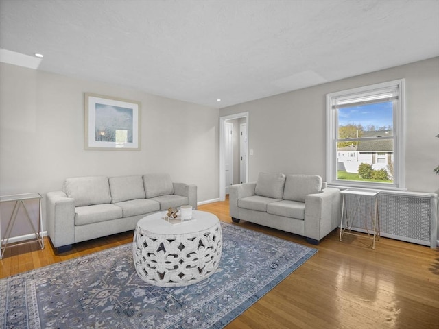 living area with recessed lighting, baseboards, radiator heating unit, and wood finished floors