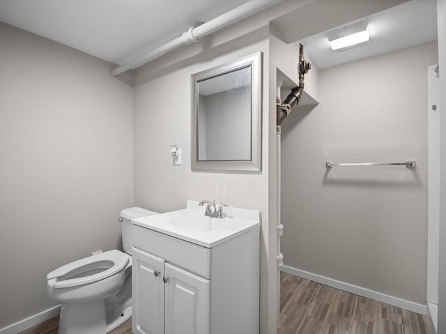 half bath featuring toilet, baseboards, wood finished floors, and vanity