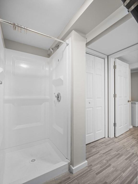 bathroom featuring baseboards, a stall shower, and wood finished floors