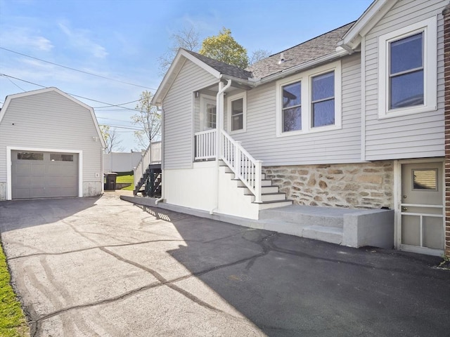 exterior space featuring stairs, a garage, an outbuilding, and concrete driveway