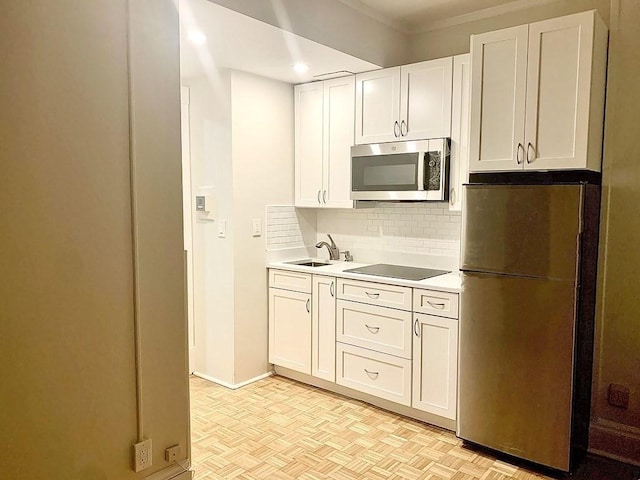 kitchen featuring appliances with stainless steel finishes, tasteful backsplash, a sink, light countertops, and white cabinetry