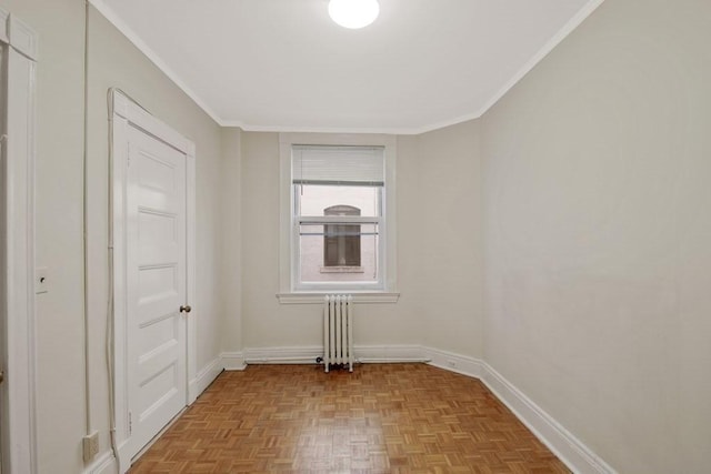 spare room featuring radiator, crown molding, and baseboards