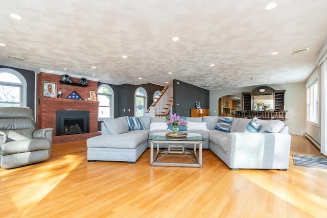 87 Lewis Point Rd, Bourne, MA 02532 - living room with arched walkways, a baseboard heating unit, recessed lighting, a brick fireplace, and healthy amount of natural light