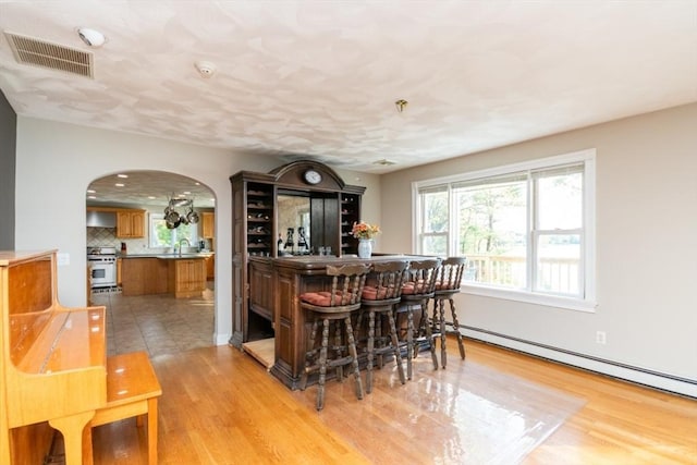 87 Lewis Point Rd, Bourne, MA 02532 - indoor dry bar featuring arched walkways, stove, a baseboard heating unit, light wood-style floors, and backsplash