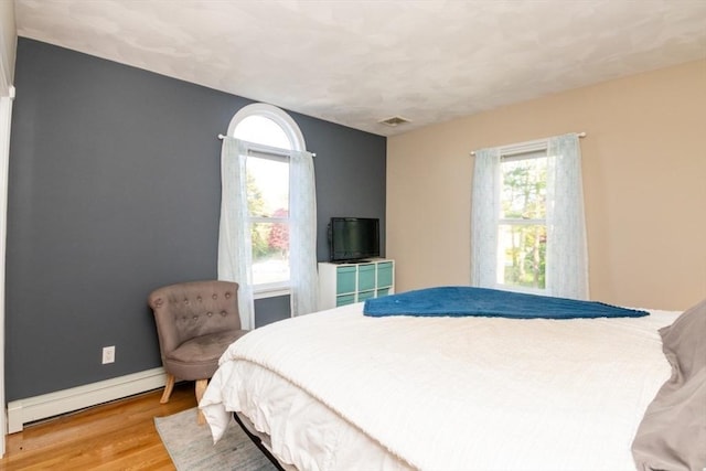 87 Lewis Point Rd, Bourne, MA 02532 - bedroom featuring a baseboard radiator, multiple windows, wood finished floors, and baseboards