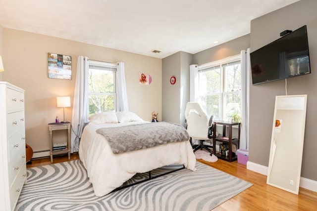 87 Lewis Point Rd, Bourne, MA 02532 - bedroom featuring multiple windows, light wood-style floors, a baseboard heating unit, and baseboards