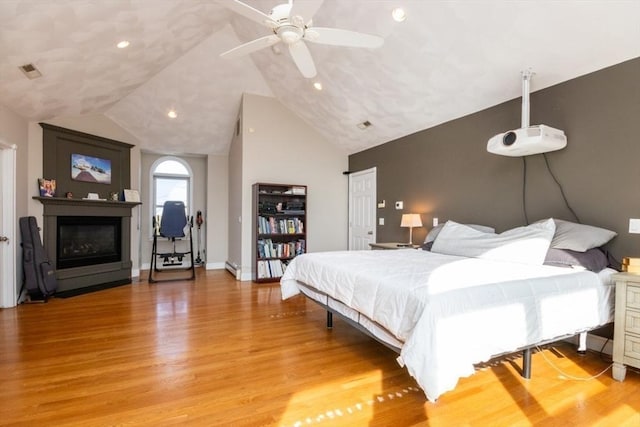 87 Lewis Point Rd, Bourne, MA 02532 - bedroom featuring light wood finished floors, a glass covered fireplace, vaulted ceiling, baseboards, and recessed lighting