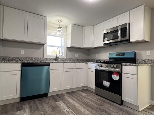 kitchen featuring pendant lighting, white cabinetry, dark wood-type flooring, and stainless steel appliances