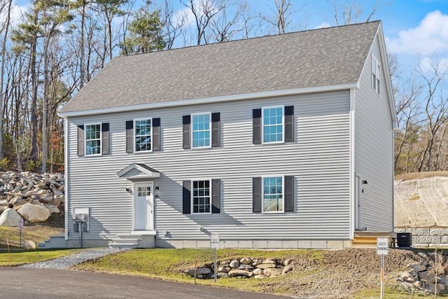colonial-style house with central AC unit, entry steps, and roof with shingles