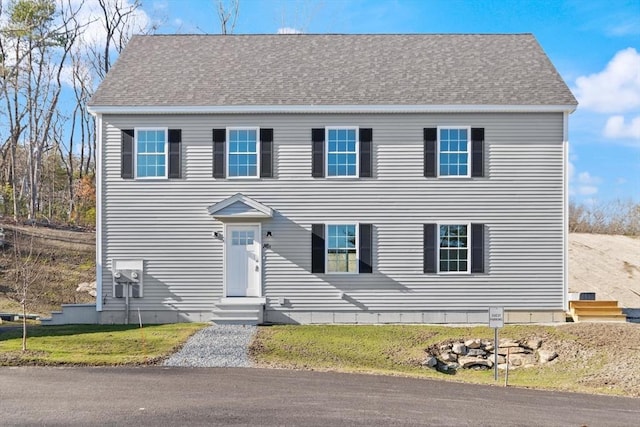 colonial house with entry steps, a front lawn, and a shingled roof