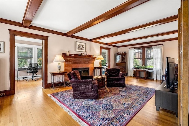 living area with plenty of natural light, a baseboard radiator, a brick fireplace, and beamed ceiling