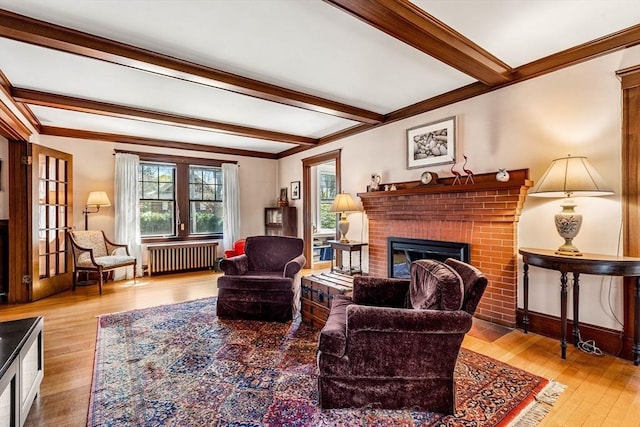 living room featuring ornamental molding, hardwood / wood-style floors, a fireplace, beamed ceiling, and radiator heating unit