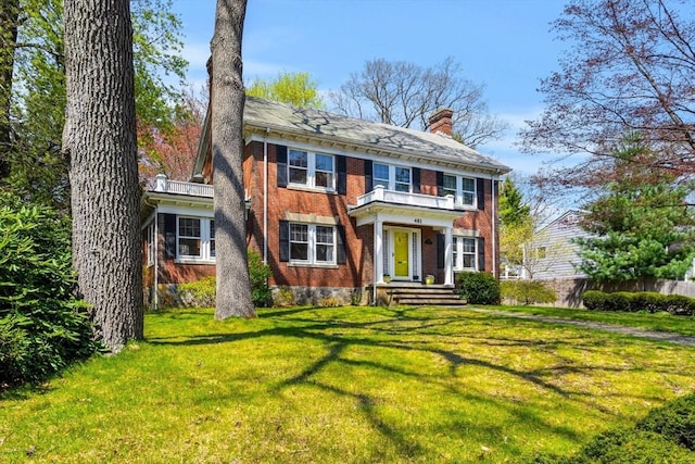 view of front of property with brick siding, fence, a chimney, and a front yard