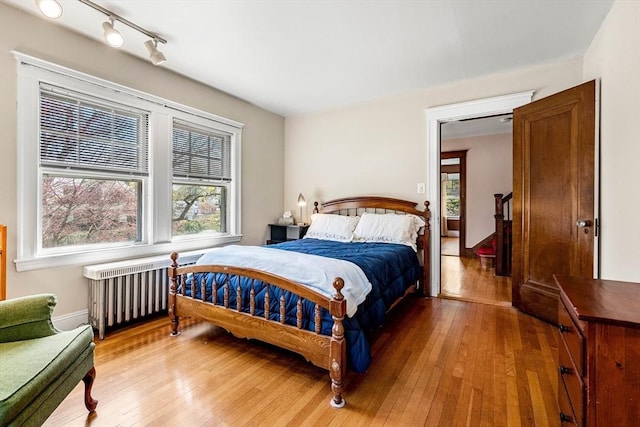 bedroom featuring radiator, rail lighting, and hardwood / wood-style floors