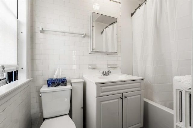 full bath featuring shower / bath combination with curtain, tile walls, vanity, toilet, and radiator