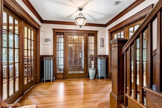 doorway featuring french doors, radiator, a wainscoted wall, and a healthy amount of sunlight