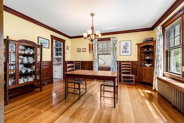 dining area featuring radiator, wainscoting, a notable chandelier, and a healthy amount of sunlight