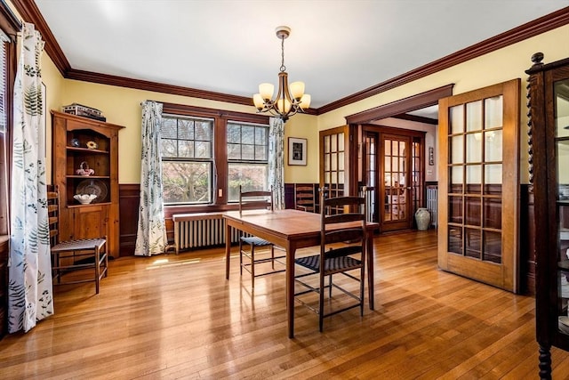 dining space with crown molding, a wainscoted wall, and a chandelier