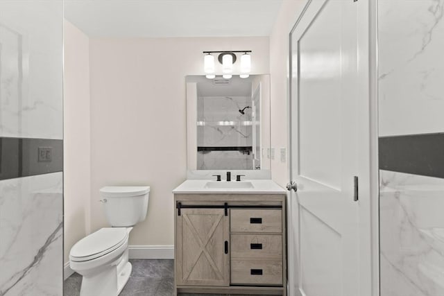 full bathroom with a marble finish shower, toilet, baseboards, and vanity