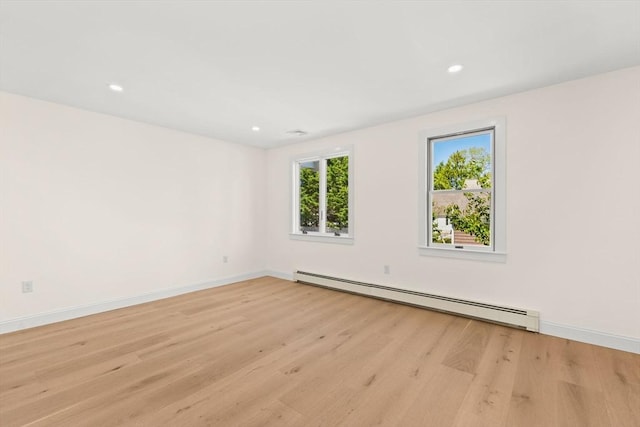 empty room with a baseboard heating unit, light wood-style flooring, baseboards, and recessed lighting