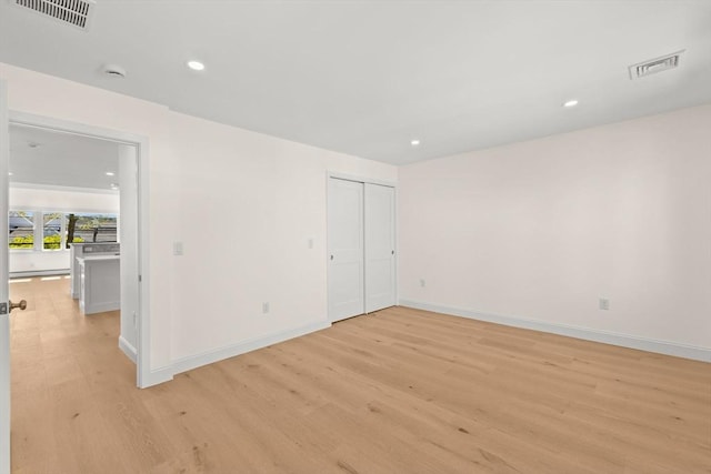 unfurnished bedroom with light wood-style floors, baseboards, recessed lighting, and a closet