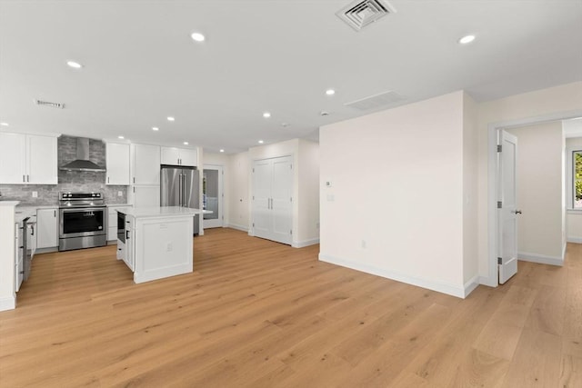 kitchen with stainless steel appliances, wall chimney exhaust hood, decorative backsplash, recessed lighting, and baseboards