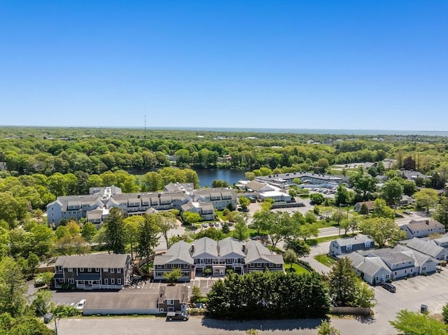 aerial perspective of suburban area featuring a nearby body of water and a heavily wooded area