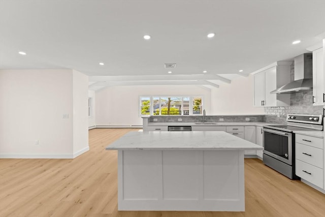 kitchen featuring appliances with stainless steel finishes, wall chimney range hood, a kitchen island, tasteful backsplash, and recessed lighting