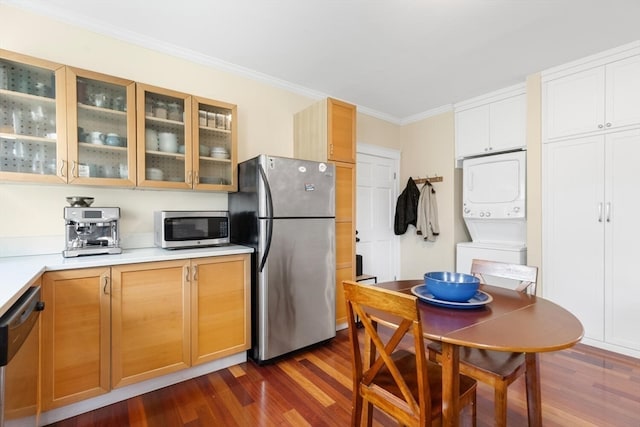 kitchen with stacked washer and dryer, crown molding, appliances with stainless steel finishes, and dark hardwood / wood-style floors