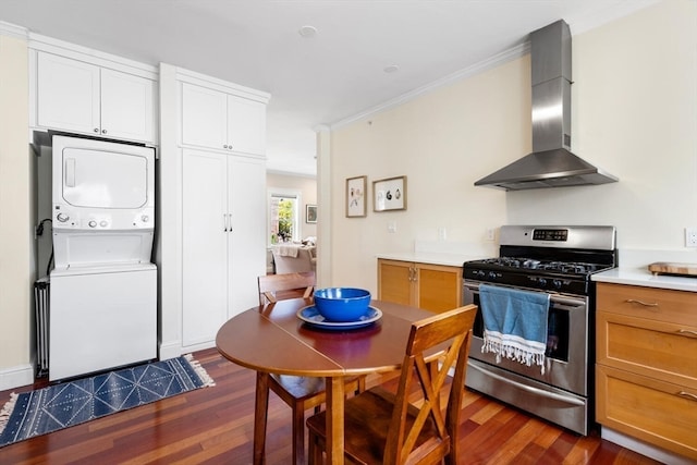 kitchen featuring wall chimney range hood, stacked washer and clothes dryer, gas range, ornamental molding, and dark hardwood / wood-style flooring