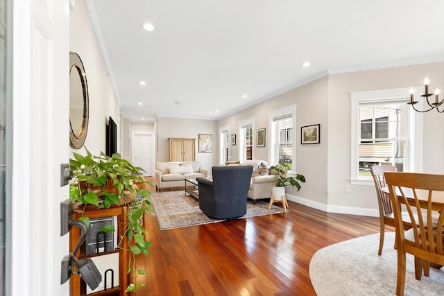 living room with crown molding, hardwood / wood-style flooring, and an inviting chandelier