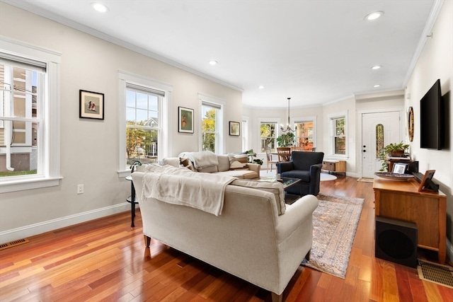 living room featuring crown molding, an inviting chandelier, and hardwood / wood-style floors