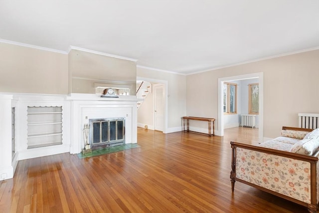 unfurnished living room featuring crown molding, wood-type flooring, and radiator heating unit