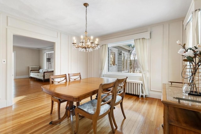 dining room with a notable chandelier, wood-type flooring, and radiator heating unit