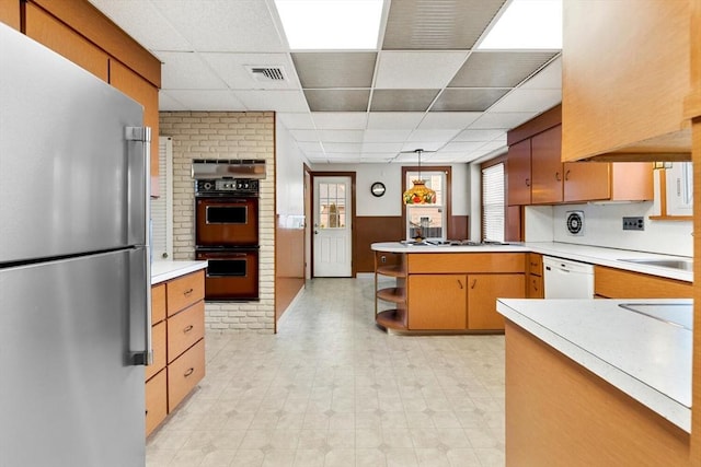 kitchen with pendant lighting, kitchen peninsula, sink, white appliances, and a paneled ceiling