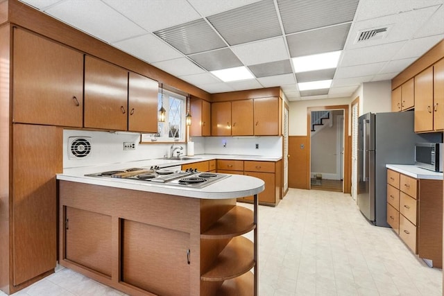 kitchen with a paneled ceiling, appliances with stainless steel finishes, kitchen peninsula, and sink