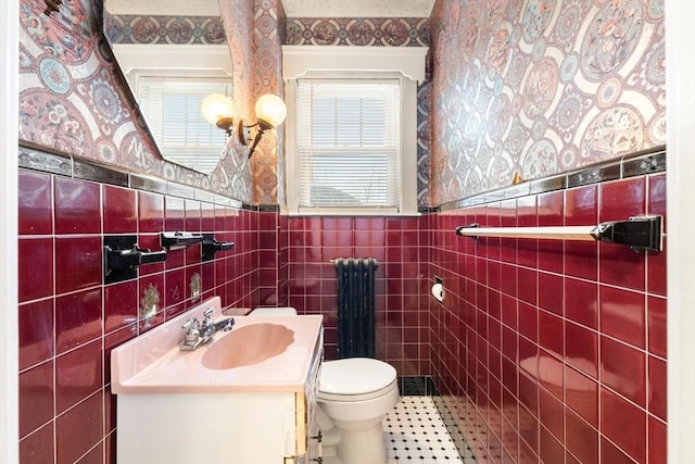 bathroom with toilet, radiator, tile walls, and vanity